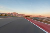 a photo of a dirt race track with sun setting in the distance of the track