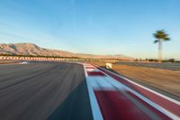 a photo of a dirt race track with sun setting in the distance of the track