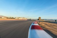 a photo of a dirt race track with sun setting in the distance of the track