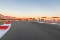 a photo of a dirt race track with sun setting in the distance of the track