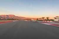 a photo of a dirt race track with sun setting in the distance of the track