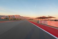 a photo of a dirt race track with sun setting in the distance of the track