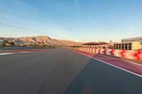 a photo of a dirt race track with sun setting in the distance of the track