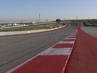 an empty track at a motorsports club with some red and white stripeing on it