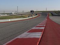 an empty track at a motorsports club with some red and white stripeing on it