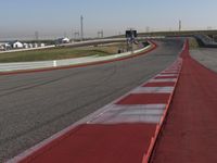 an empty track at a motorsports club with some red and white stripeing on it