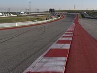 an empty track at a motorsports club with some red and white stripeing on it