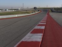 an empty track at a motorsports club with some red and white stripeing on it