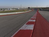 an empty track at a motorsports club with some red and white stripeing on it