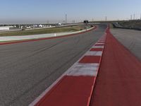 an empty track at a motorsports club with some red and white stripeing on it