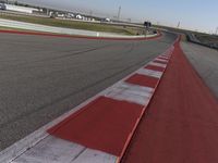 an empty track at a motorsports club with some red and white stripeing on it