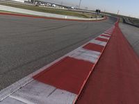 an empty track at a motorsports club with some red and white stripeing on it