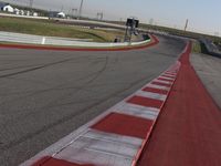 an empty track at a motorsports club with some red and white stripeing on it