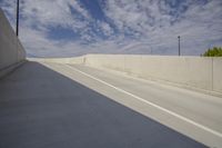 a long gray highway with an overpass leading to it and a white fence surrounding it