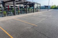 a storefront in an empty parking lot with bicycles outside of it and parked cars behind