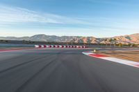 a photo of a dirt race track with sun setting in the distance of the track