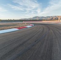 a photo of a dirt race track with sun setting in the distance of the track