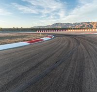 a photo of a dirt race track with sun setting in the distance of the track