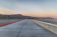 a photo of a dirt race track with sun setting in the distance of the track