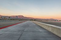 a photo of a dirt race track with sun setting in the distance of the track