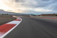 a photo of a dirt race track with sun setting in the distance of the track