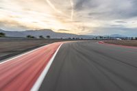 a photo of a dirt race track with sun setting in the distance of the track