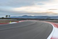 a photo of a dirt race track with sun setting in the distance of the track