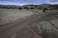 the view of a dirt road from the top of a hill covered with rocks and scrub