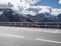 a person skateboarding in front of mountains on a road lined with snow capped mountains