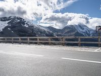 a person skateboarding in front of mountains on a road lined with snow capped mountains