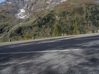 a person on a motorcycle is riding down the street near a mountain backdrop and road markings