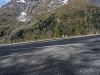 a person on a motorcycle is riding down the street near a mountain backdrop and road markings