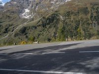 a person on a motorcycle is riding down the street near a mountain backdrop and road markings