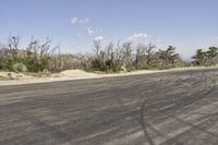 a view along a dirt road of an empty field and mountains in the distance of the scene