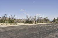 a view along a dirt road of an empty field and mountains in the distance of the scene