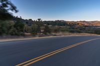 a person riding on the back of a motorcycle down an empty road next to mountains