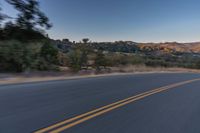 a person riding on the back of a motorcycle down an empty road next to mountains