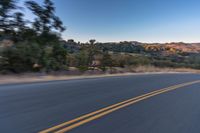 a person riding on the back of a motorcycle down an empty road next to mountains