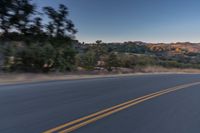 a person riding on the back of a motorcycle down an empty road next to mountains