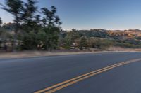 a person riding on the back of a motorcycle down an empty road next to mountains