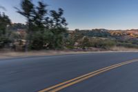 a person riding on the back of a motorcycle down an empty road next to mountains