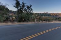 a person riding on the back of a motorcycle down an empty road next to mountains