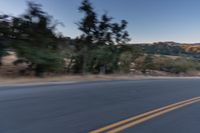 a person riding on the back of a motorcycle down an empty road next to mountains