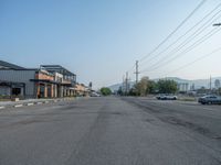 the empty street outside of the business district is empty and deserted with vehicles parked in it