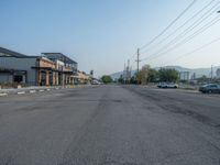 the empty street outside of the business district is empty and deserted with vehicles parked in it