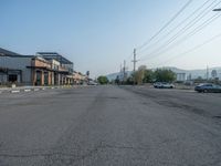 the empty street outside of the business district is empty and deserted with vehicles parked in it