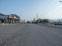 the empty street outside of the business district is empty and deserted with vehicles parked in it