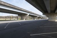 a large bridge going over a parking lot next to an empty road for cars to drive across