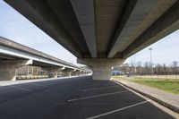 a large bridge going over a parking lot next to an empty road for cars to drive across