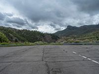 a mountain sits in the distance in a parking lot with a few trees and shrubbery